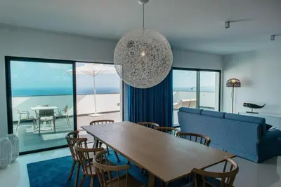 a living room with a table and a blue couch at Vilas Mediterrâneo in Santa Cruz