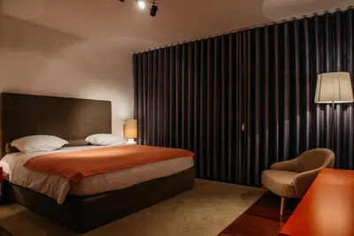 a bedroom with a large bed and a chair at Vilas Mediterrâneo in Santa Cruz