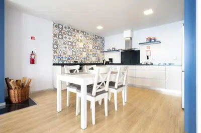 a white kitchen with a white table and chairs at Apartamento Goncalves in Arco da Calheta