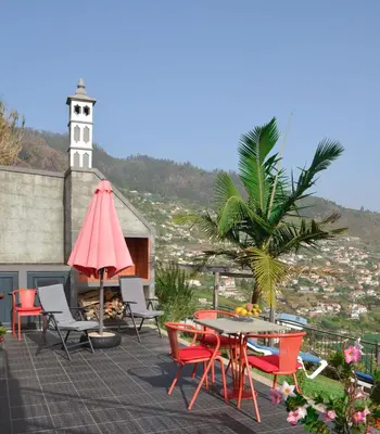 a patio with a table and chairs and a clock tower at Casa Horizonte in Arco da Calheta