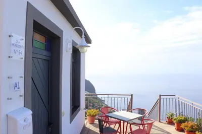 a balcony with a table and chairs and the ocean at Casa Horizonte in Arco da Calheta