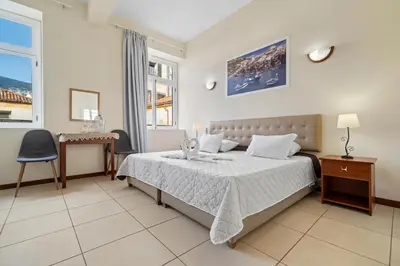 a bedroom with a bed and a desk and a window at Alojamento Local Trigal in Funchal