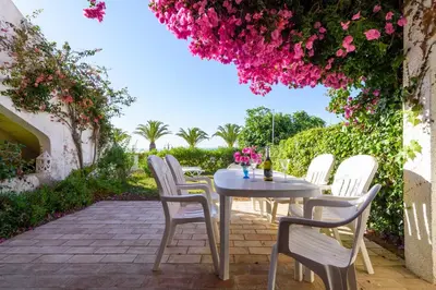 a table and chairs on a patio with pink flowers at Casa Sol e Praia in Luz