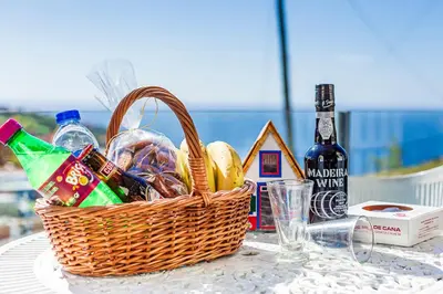 a basket of food and a bottle of wine on a table at Vila Morning Sun in Calheta