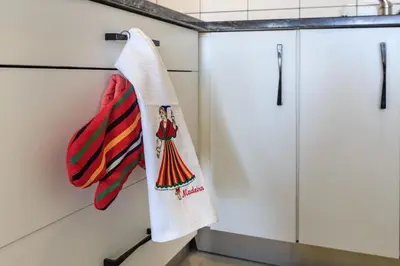a kitchen with white cabinets and a towel on the wall at Vila Morning Sun in Calheta
