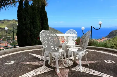 three white chairs and a table with a view of the ocean at Moradia Cor de Rosa in Machico