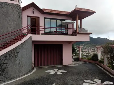 a pink house with a balcony and a driveway at Moradia Cor de Rosa in Machico