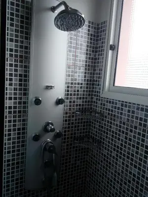 a bathroom with a shower with black tiles at Moradia Cor de Rosa in Machico