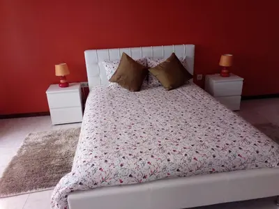 a bedroom with a white bed with red walls at Moradia Cor de Rosa in Machico