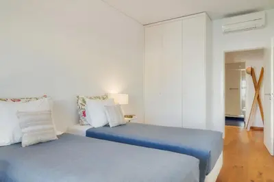 two beds in a room with white walls and wood floors at Casa da Praça Apartments - by Casas na Ilha in Funchal