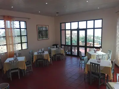 a dining room with tables and chairs and windows at Estalagem Corte do Norte in Ponta Delgada