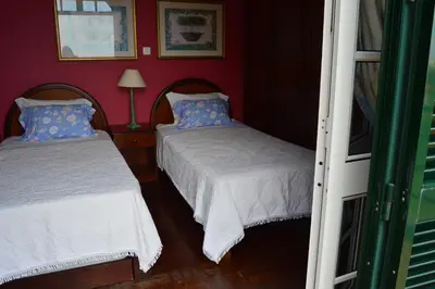 two beds in a room with red walls at Estalagem Corte do Norte in Ponta Delgada