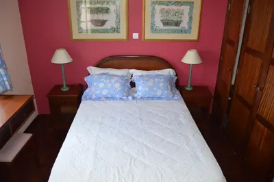 a bedroom with a white bed with blue pillows at Estalagem Corte do Norte in Ponta Delgada