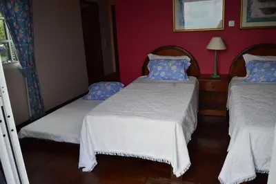 a bedroom with two beds and a red wall at Estalagem Corte do Norte in Ponta Delgada