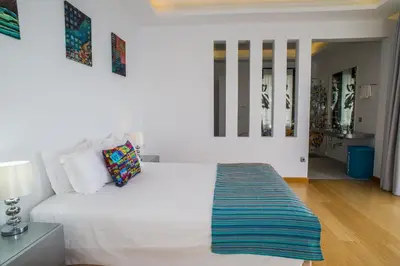 a bedroom with a white bed with a blue rug on it at Ocean Cliff in Ponta do Sol
