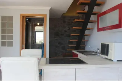 a kitchen with a counter with a microwave and a staircase at Crystal House in Calheta