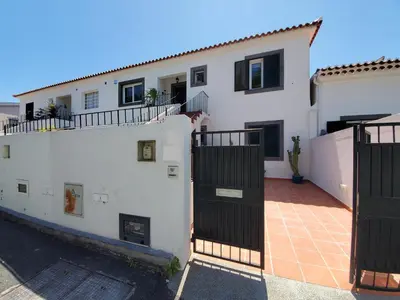 a white house with black gates and a courtyard at Murteiras Living in Funchal