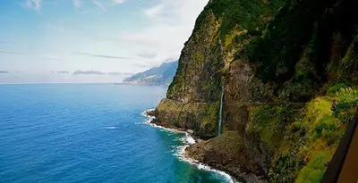 a cliff next to the ocean with a mountain at Rooftop Apartment city center in Funchal