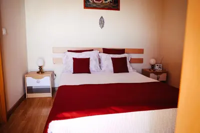 a bedroom with a large bed with a red blanket at Raposeira Chloe T2 in Fajã da Ovelha