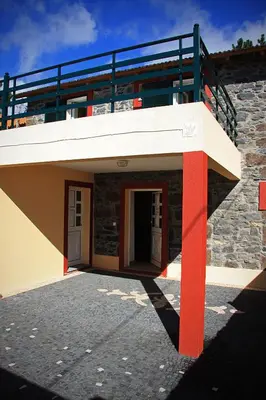 a building with red columns and a balcony at Raposeira Chloe T2 in Fajã da Ovelha