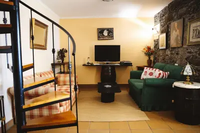a living room with a green couch and a television at Raposeira Chloe T2 in Fajã da Ovelha