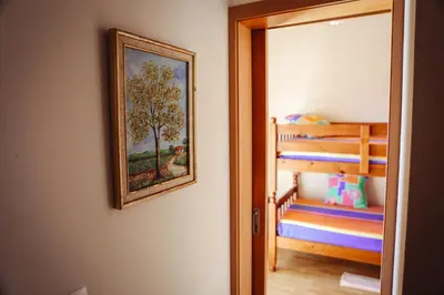 a bedroom with a painting on the wall and a bunk bed at Raposeira Chloe T2 in Fajã da Ovelha