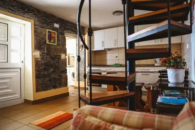 a kitchen and a living room with a spiral staircase at Raposeira Chloe T2 in Fajã da Ovelha