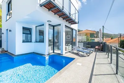 a villa with a swimming pool and a house at Hillside Villa in Arco da Calheta