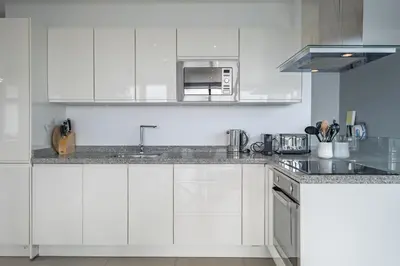 a white kitchen with a sink and a microwave at Hillside Villa in Arco da Calheta