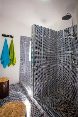 a shower with a glass door in a bathroom at The Pallet - Guest House in Santa Cruz