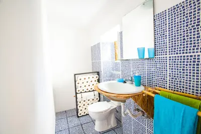 a bathroom with a sink and a toilet and a mirror at The Pallet - Guest House in Santa Cruz
