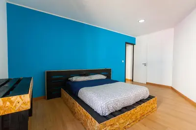 a bedroom with a bed with a blue wall at The Pallet - Guest House in Santa Cruz