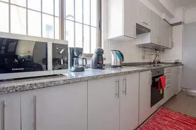 a kitchen with white cabinets and a large window at Caniço I By Trip2Portugal in Caniço