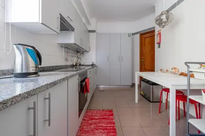 a kitchen with white cabinets and a red rug at Caniço I By Trip2Portugal in Caniço
