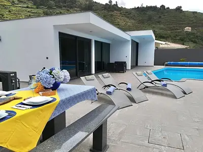 a dining table and chairs next to a pool at Moradia Syso in Arco da Calheta