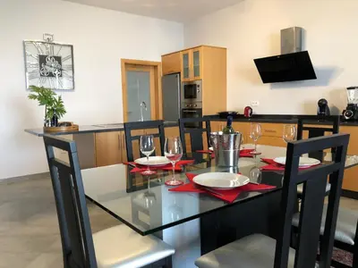 a dining room and kitchen with a glass table and chairs at Moradia Syso in Arco da Calheta