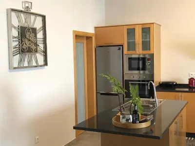 a kitchen with a black counter top and a refrigerator at Moradia Syso in Arco da Calheta