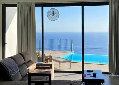 a living room with a couch and a view of a pool at Moradia Syso in Arco da Calheta