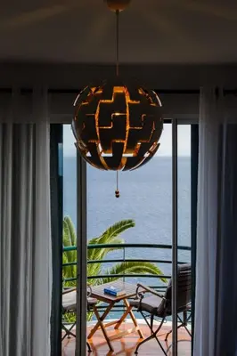 a room with a balcony with a table and a chandelier at Lobos Bay-Apartment With Unique Sea Views in Câmara de Lobos
