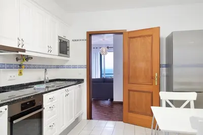 a kitchen with white cabinets and a wooden door at Lobos Bay-Apartment With Unique Sea Views in Câmara de Lobos