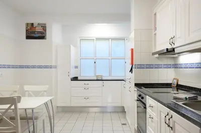 a kitchen with white cabinets and a table and a window at Lobos Bay-Apartment With Unique Sea Views in Câmara de Lobos