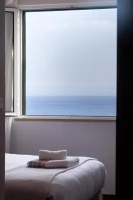 a bedroom with a window with towels on a bed at Lobos Bay-Apartment With Unique Sea Views in Câmara de Lobos