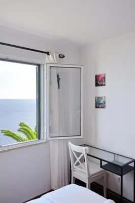 a desk and a chair in a room with a window at Lobos Bay-Apartment With Unique Sea Views in Câmara de Lobos