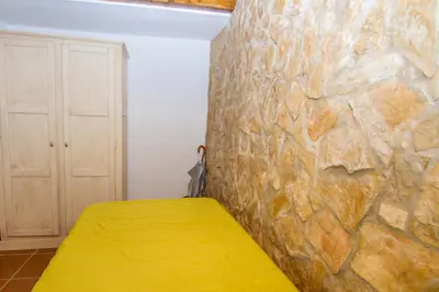 a bedroom with a stone wall and a yellow bed at Akivillas Lagos Quiet in Barão de São Miguel