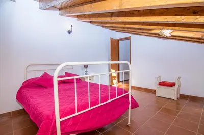 a bedroom with a bed with pink sheets and a wooden ceiling at Akivillas Lagos Quiet in Barão de São Miguel
