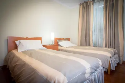 a hotel room with two beds and a window at Helen´s House Apartment in Câmara de Lobos