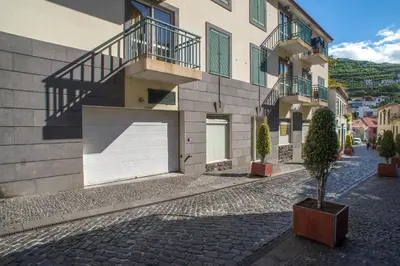 a building with a white garage door on a street at Helen´s House Apartment in Câmara de Lobos