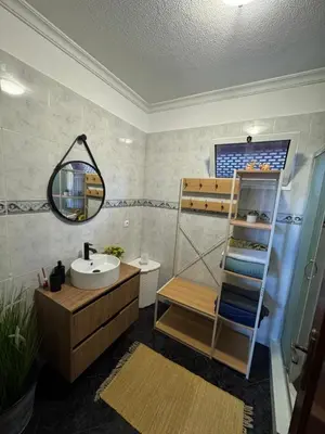 a bathroom with a sink and a shelf with towels at Ponta do Sol Villa in Ponta do Sol
