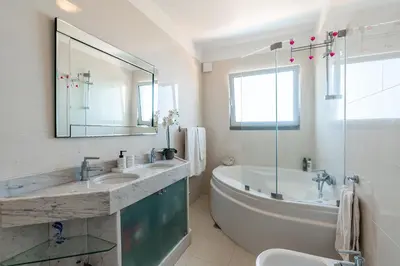 a bathroom with a tub and a large mirror at Villa Abreu - A Wonderful Ocean View in Calheta