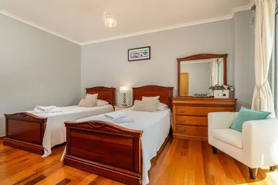 a bedroom with two beds and a chair and a mirror at Villa Abreu - A Wonderful Ocean View in Calheta